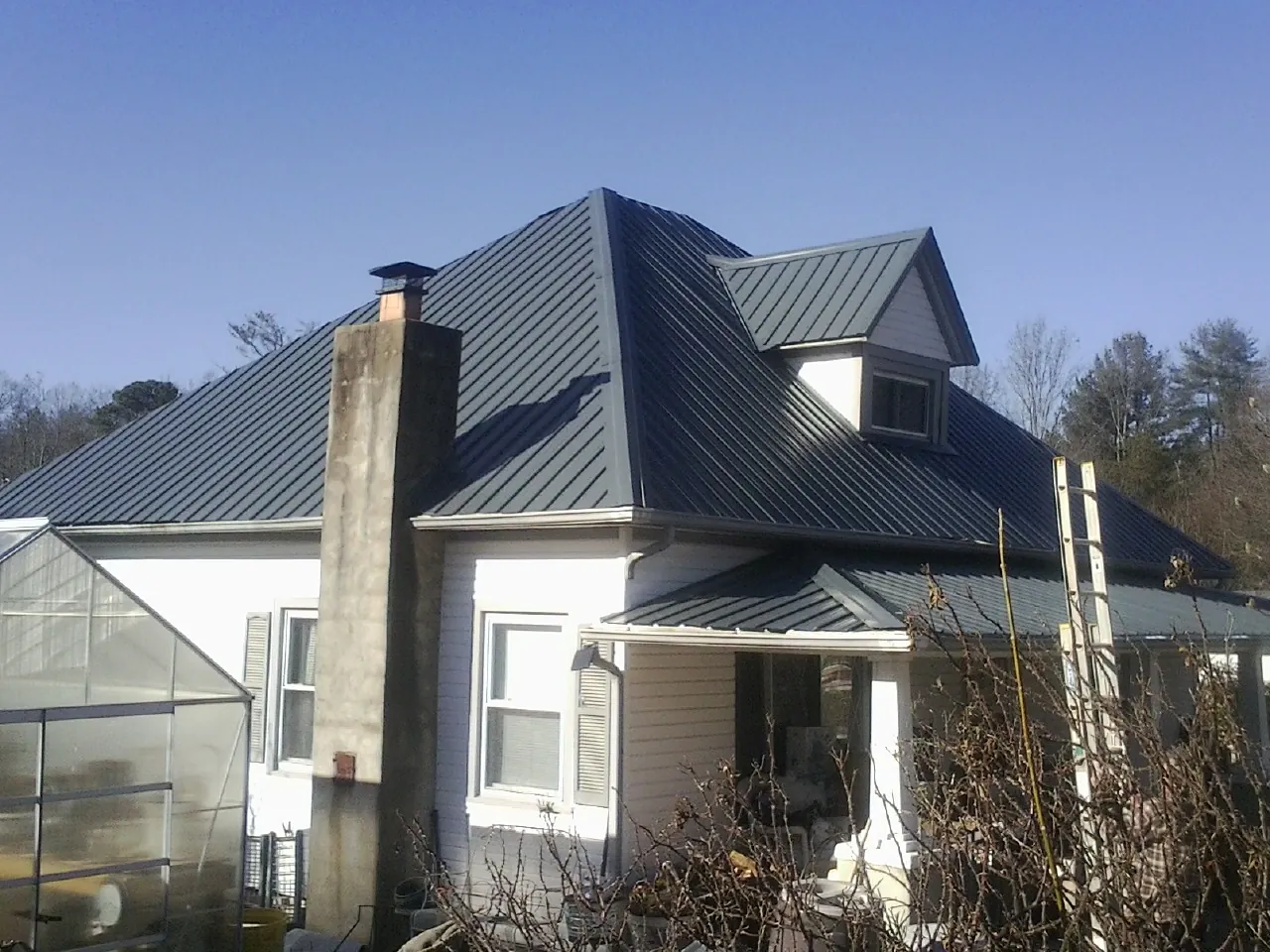 Dark blue standing seam metal roof on a white farmhouse with dormer — Slate & Tile Roof Repair by Roofing Brothers in Danville