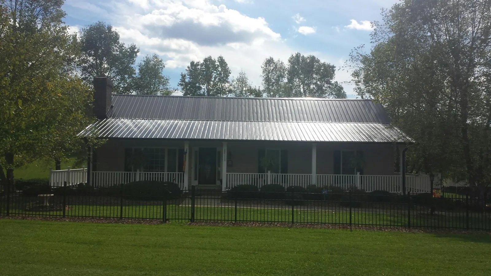 Gray metal roof on a brick ranch with a full width front porch — Gutter Guard Installation work by our crew in Danville