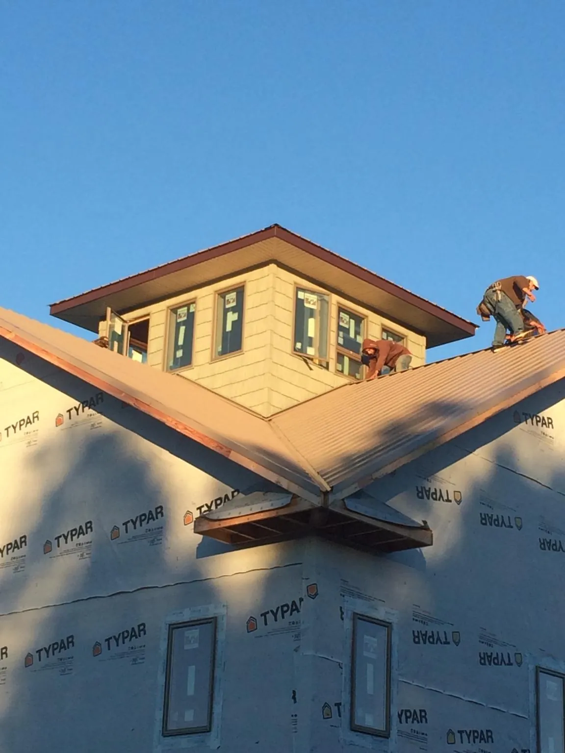 Roofers working around a rooftop cupola on a new metal roof at sunset — Roof Waterproofing in Danville by Roofing Brothers